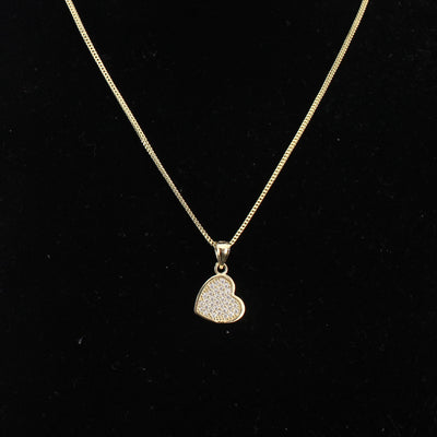 Gold necklace with a heart-shaped pendant on a black background