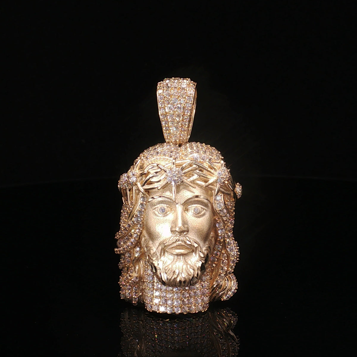 Gold pendant with a face design on a black background