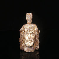 Gold pendant with a face design on a black background