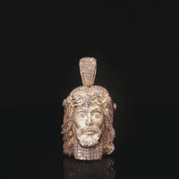 Gold pendant with a face design on a black background