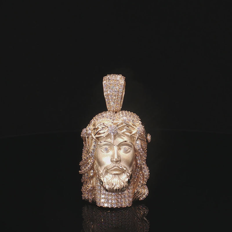 Gold pendant with a face design on a black background